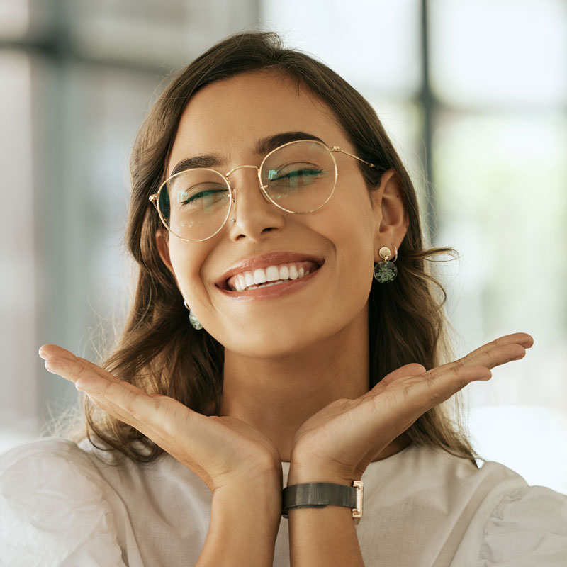 cheerful woman with glasses posing with her hands under her face showing her smile